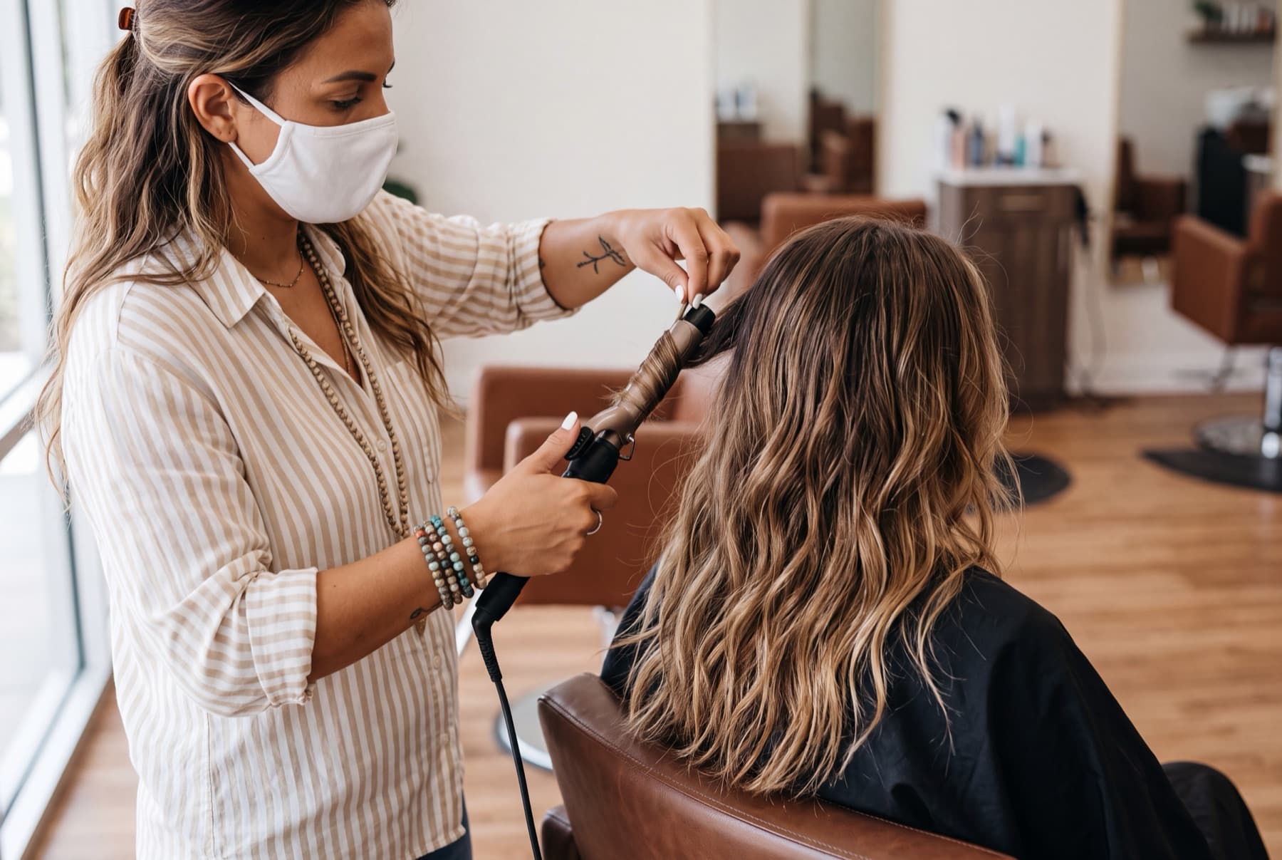 A hairstylist curling a client's hair with an iron