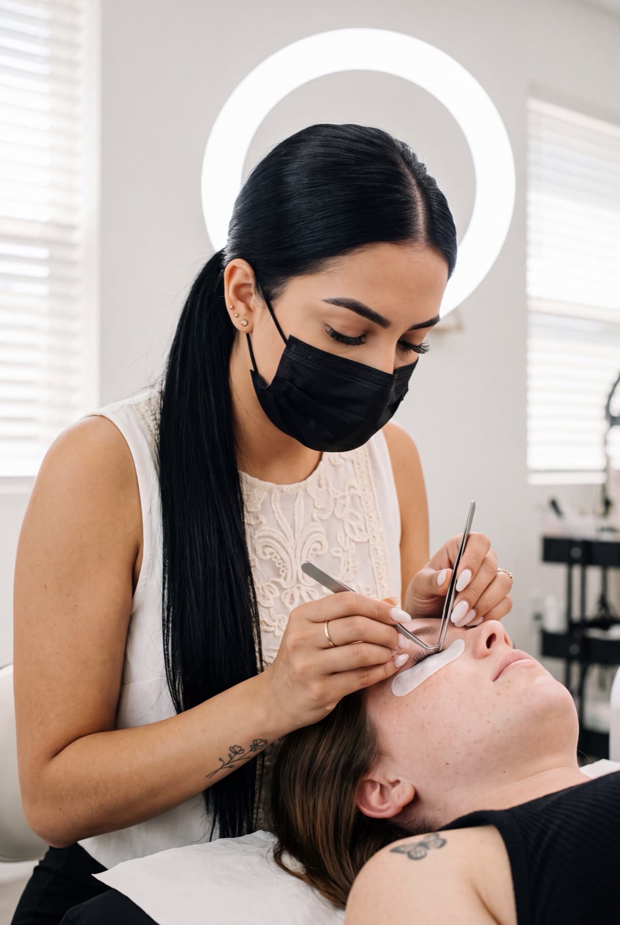 A lash artist applying eyelash extensions with tweezers