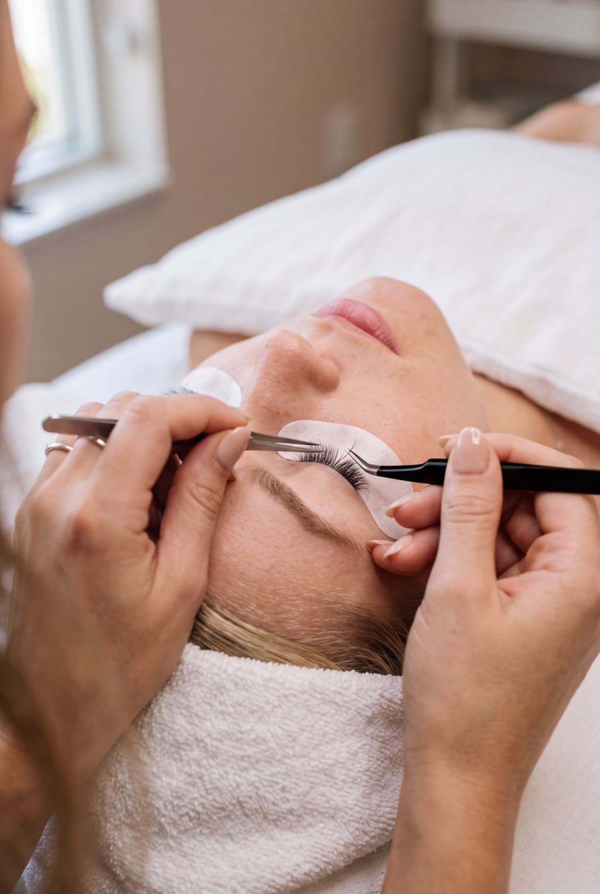 A lash artist placing extensions with tweezers