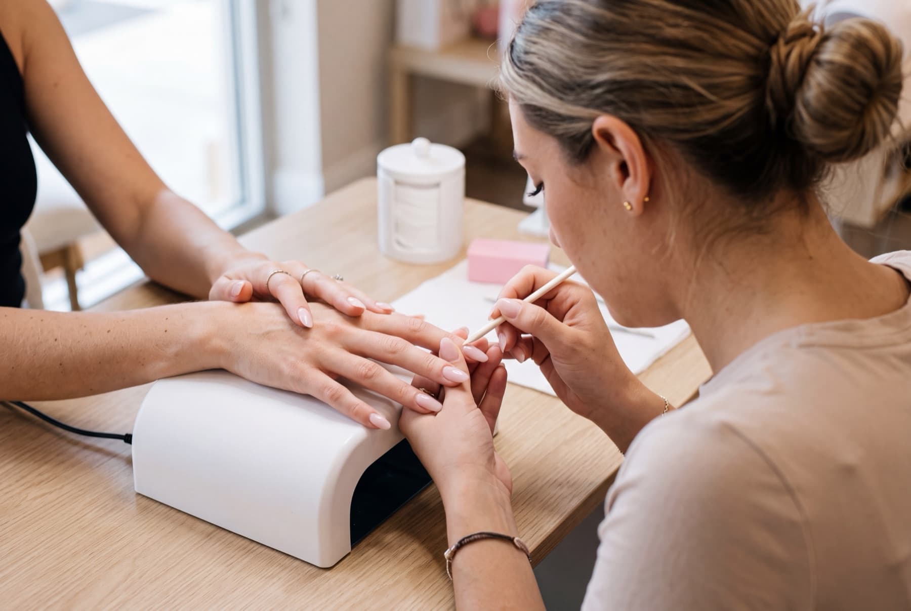 A nail technician shaping a client's nails at the station